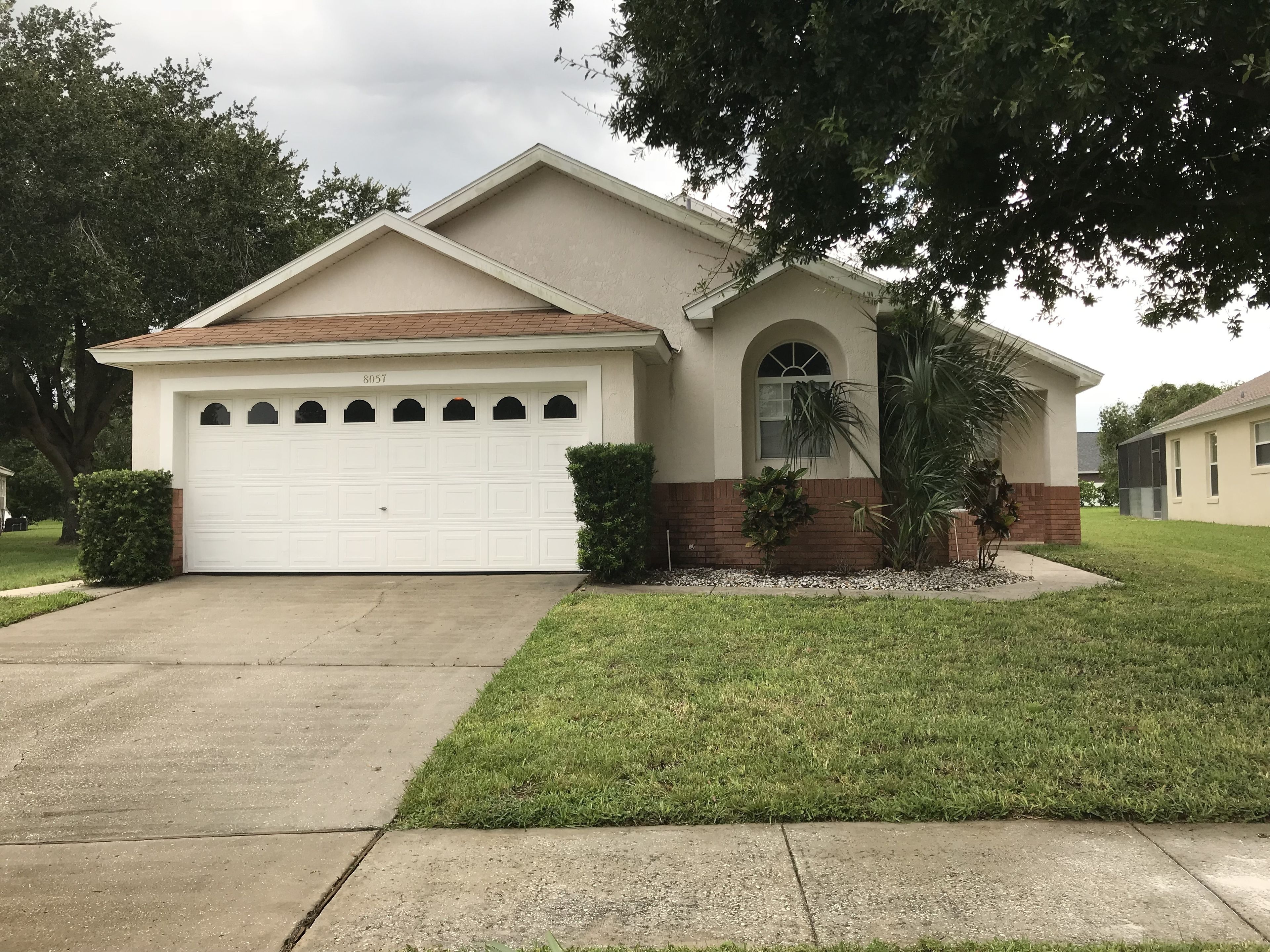 A single-story house with a garage, a front yard, and a tree.