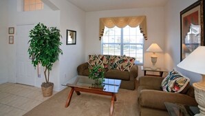 A living room with a sofa, a coffee table, a lamp, and a potted plant.