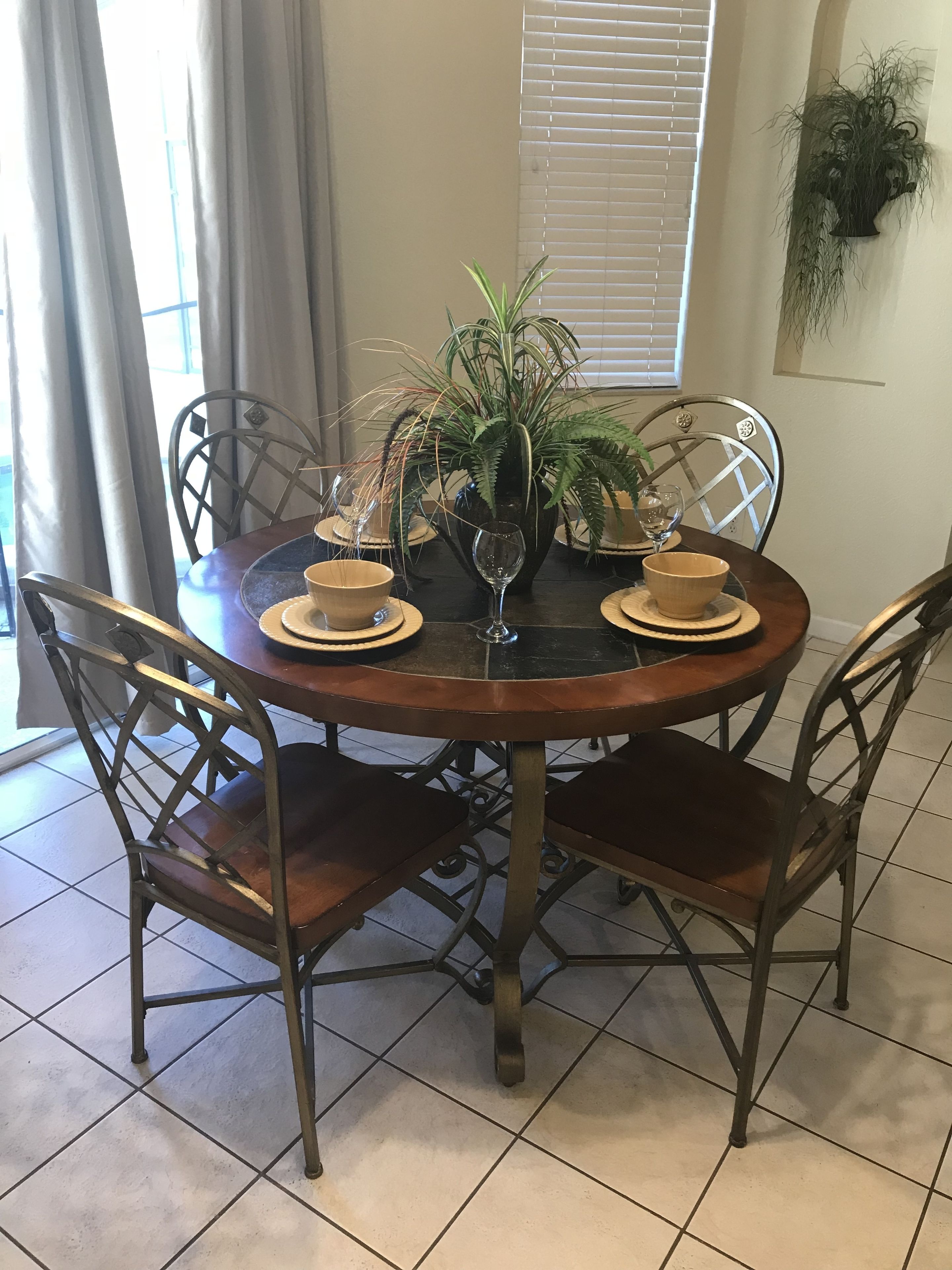 A dining table with four chairs, a potted plant, and a wine glass.