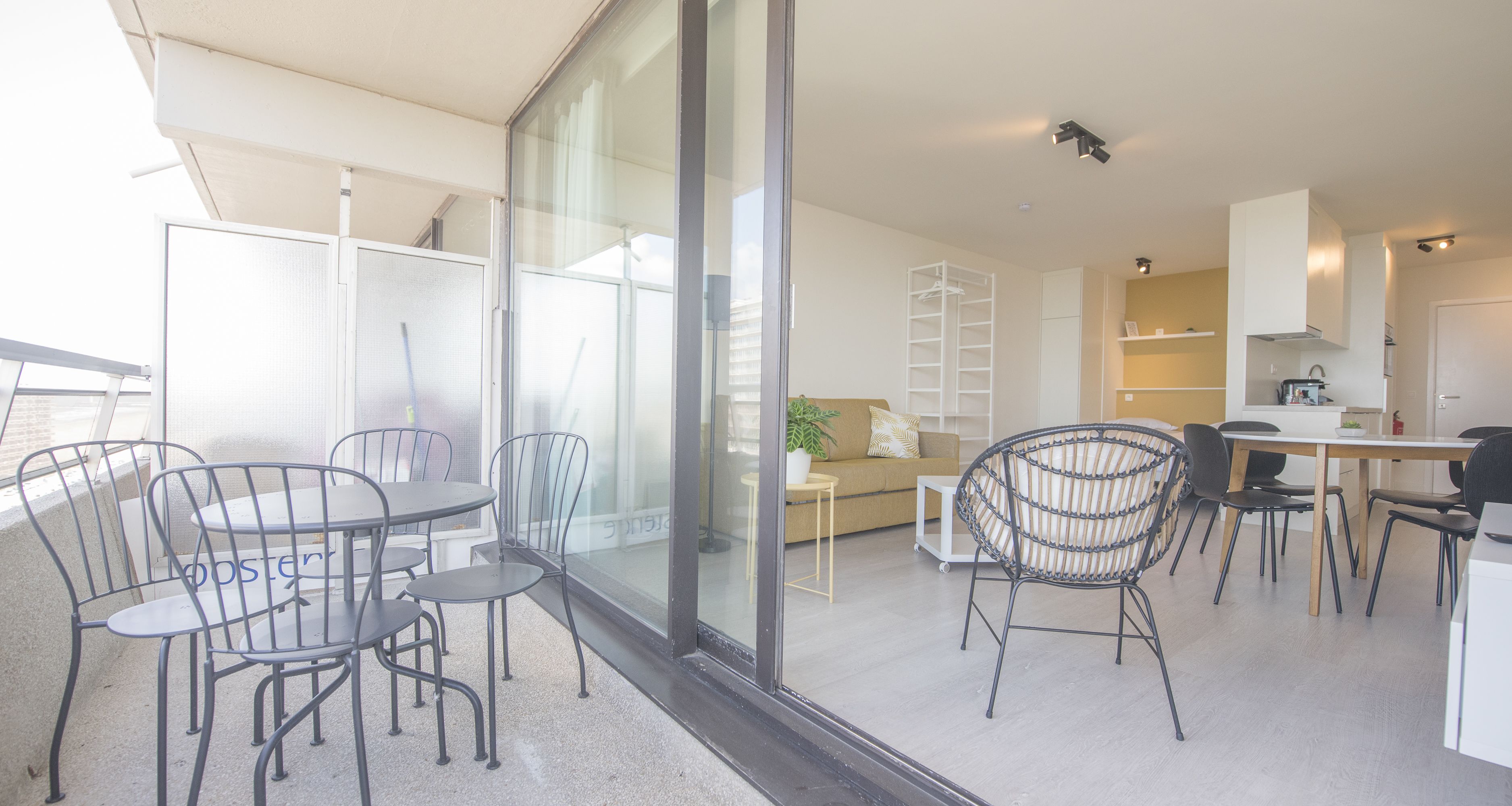 En moderne stue med balkon, spiseområde og køkken.