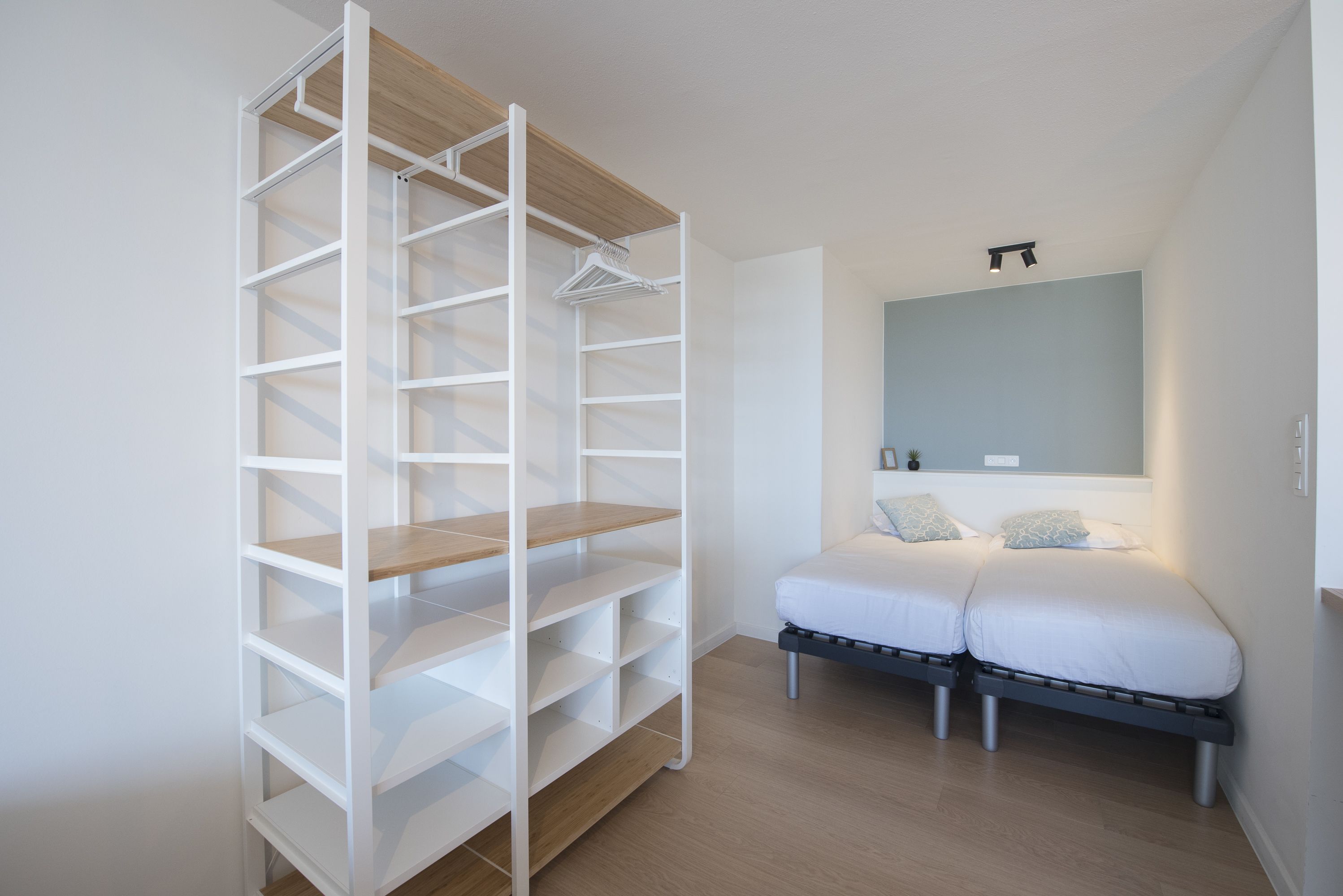 Een slaapkamer met een inbouwkast, een bed met twee kussens en een nachtkastje.