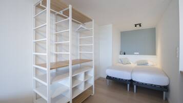 Een slaapkamer met een inbouwkast, een bed met twee kussens en een nachtkastje.