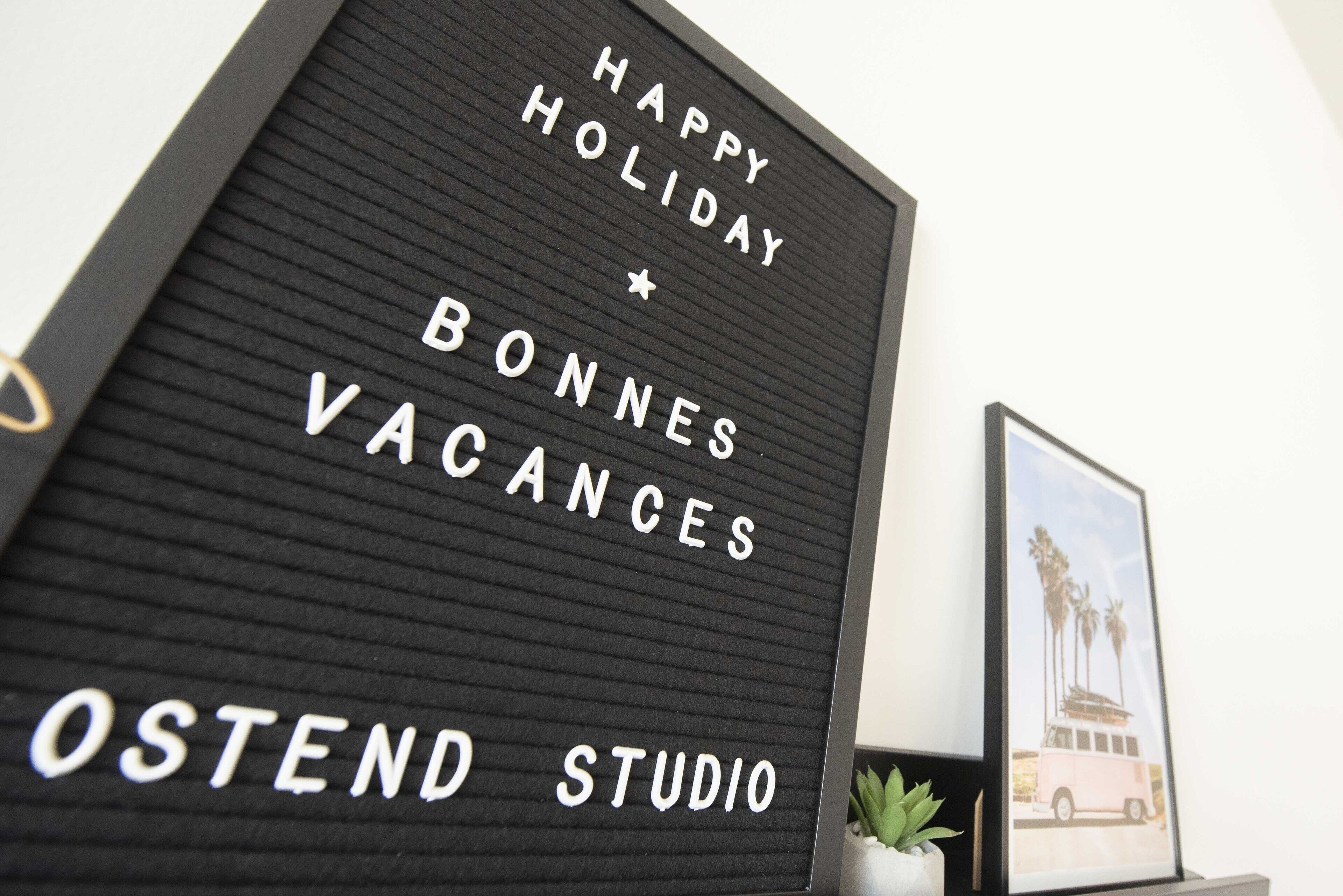 Een bord met de tekst 'HAPPY HOLIDAY' en 'BONNES VACANCES', dat een vakantiegroet aanduidt.