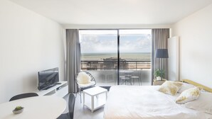 Une chambre d’hôtel comprenant un lit, un bureau, une chaise, une télévision et un balcon avec vue sur la mer.
