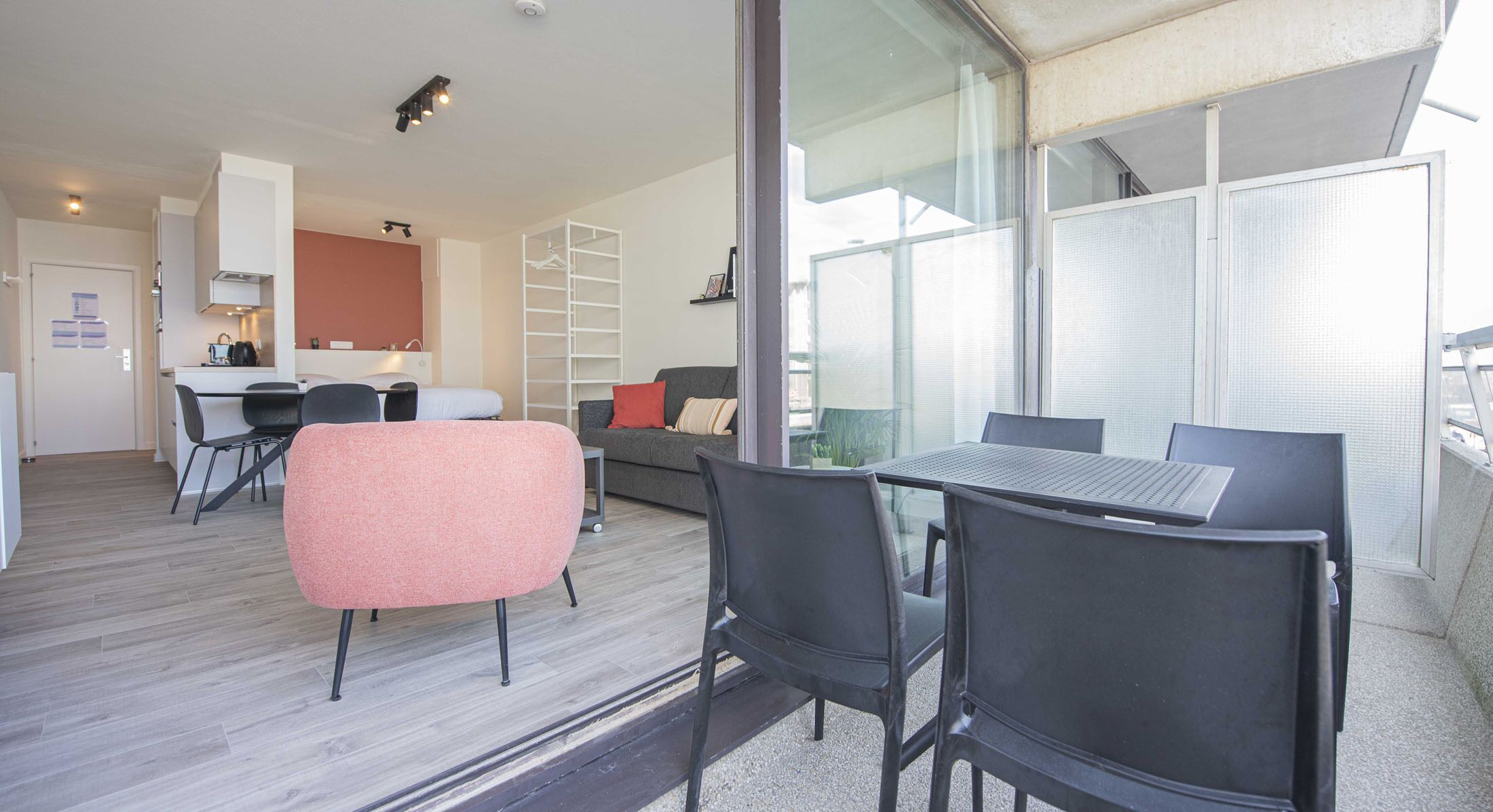 Un appartement moderne comprenant un coin repas, une cuisine et un balcon doté de grandes fenêtres.
