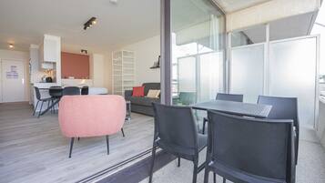 Un appartement moderne comprenant un coin repas, une cuisine et un balcon doté de grandes fenêtres.