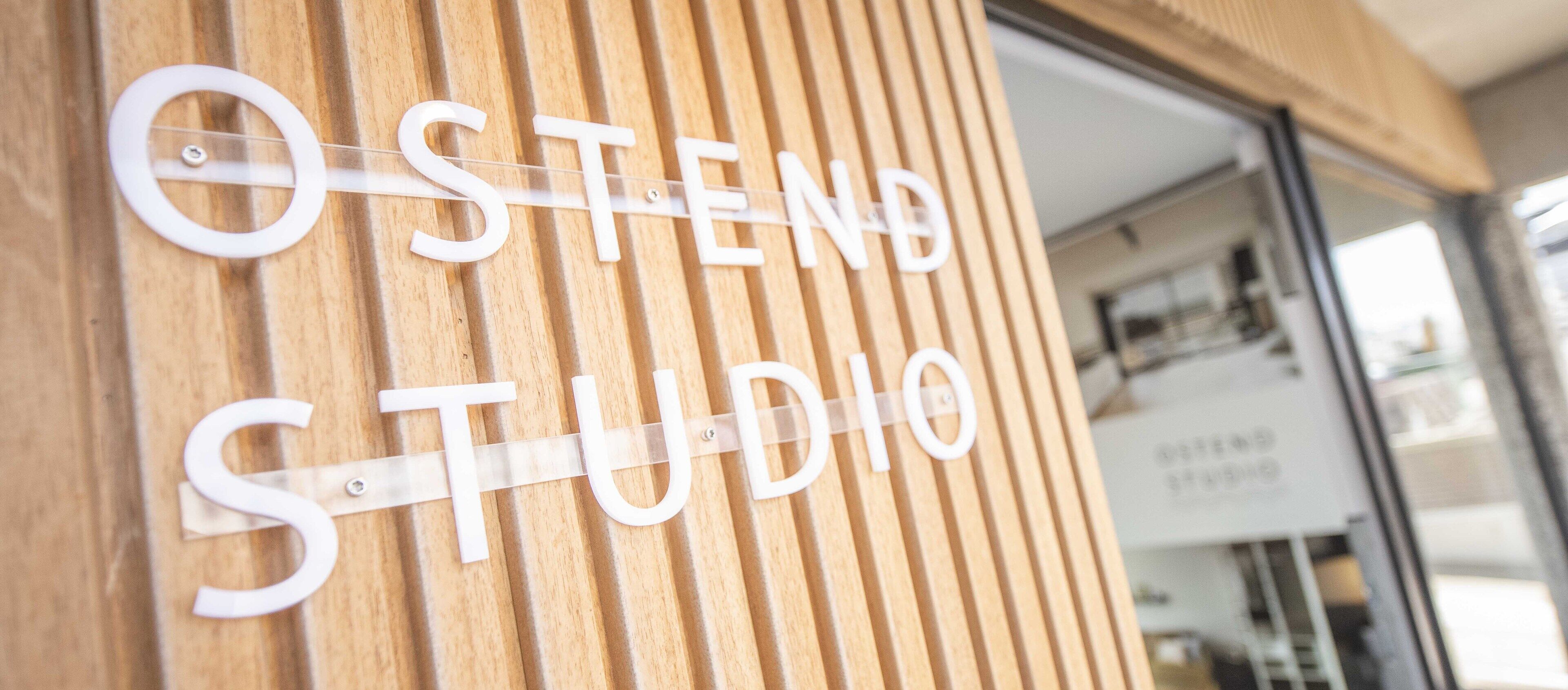 Una parete di legno con la scritta "OSTEND STUDIO" in lettere bianche.