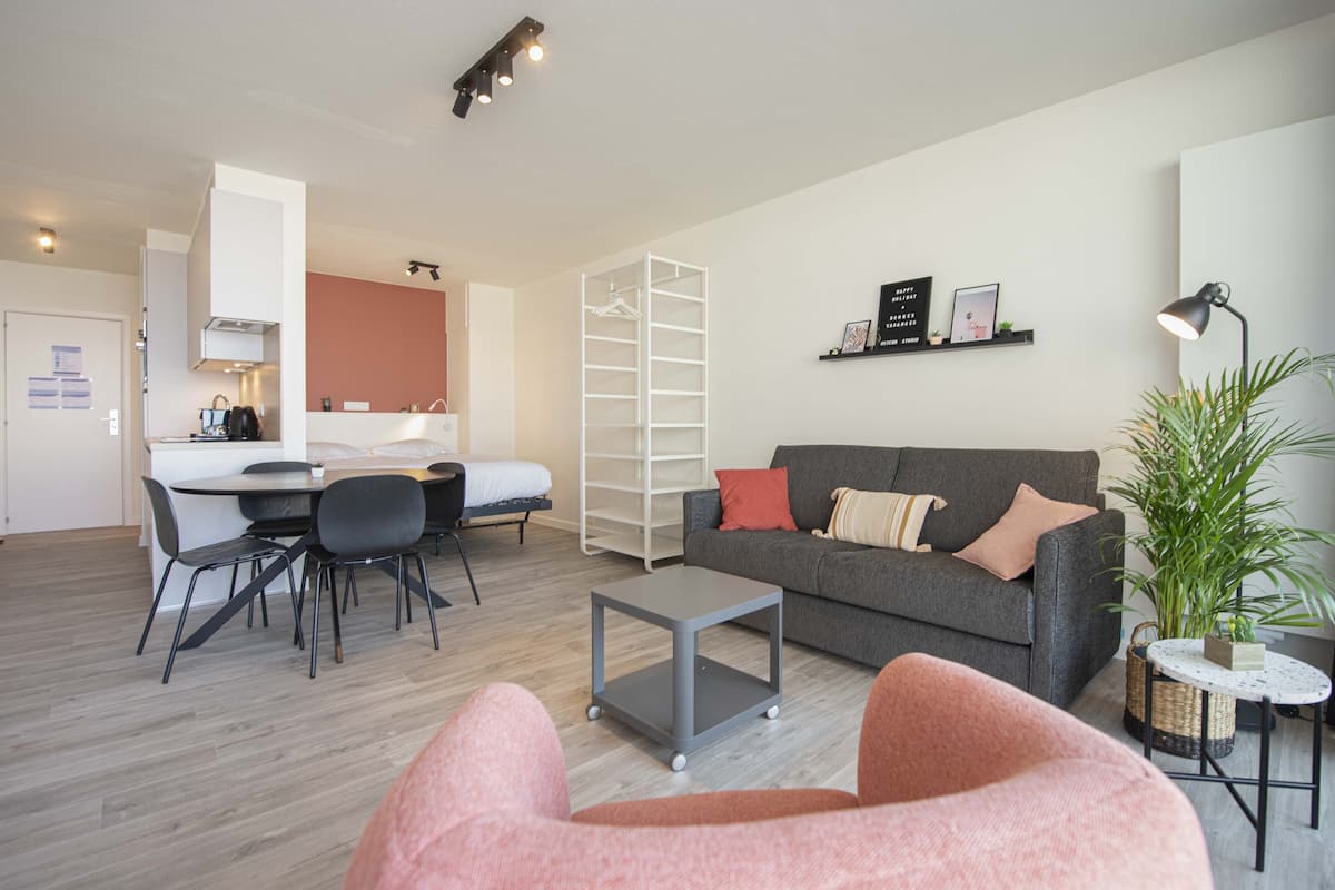 Un salon moderne avec un canapé gris, une petite table basse et un coin repas comprenant une table et des chaises.