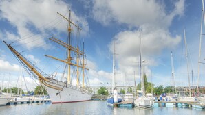 Un port de plaisance où sont amarrés de nombreux bateaux, dont un grand voilier.