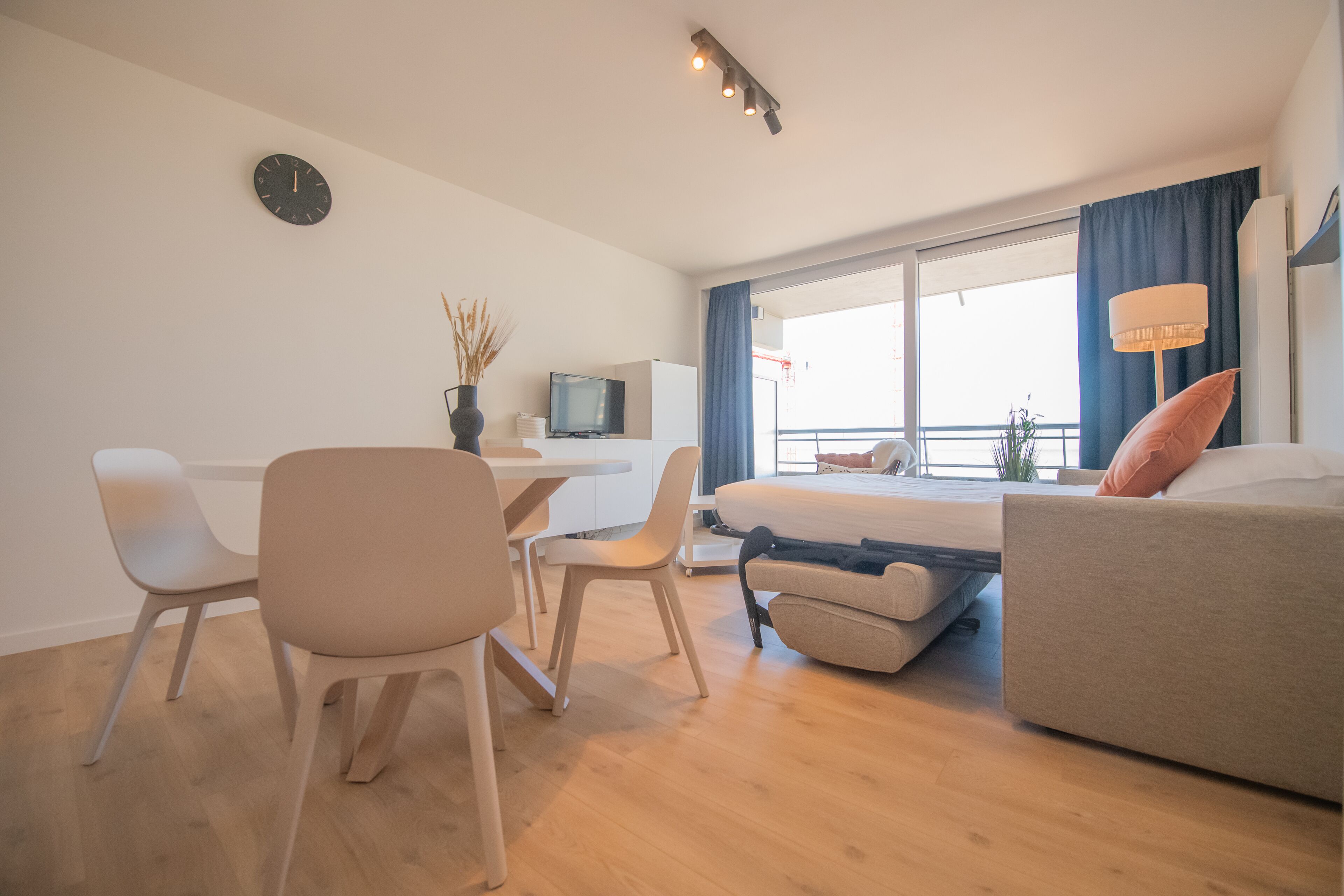 Ein modernes Hotelzimmer mit einem Bett, einem Schreibtisch, einem Stuhl, einem Fernseher und einem Fenster mit Vorhängen.