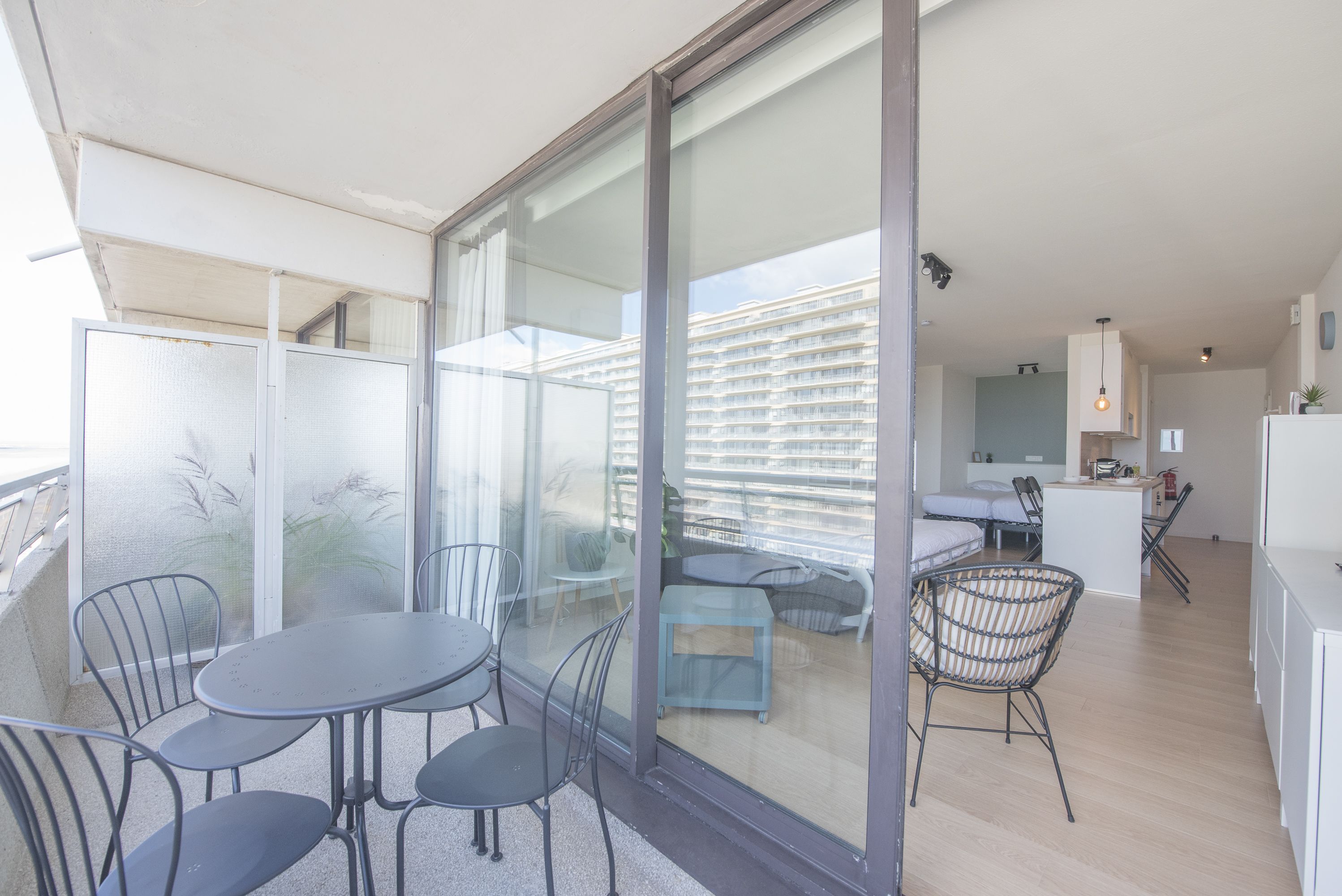 Un appartement moderne doté d’un balcon, d’un coin repas avec une table et des chaises, et d’un espace cuisine.