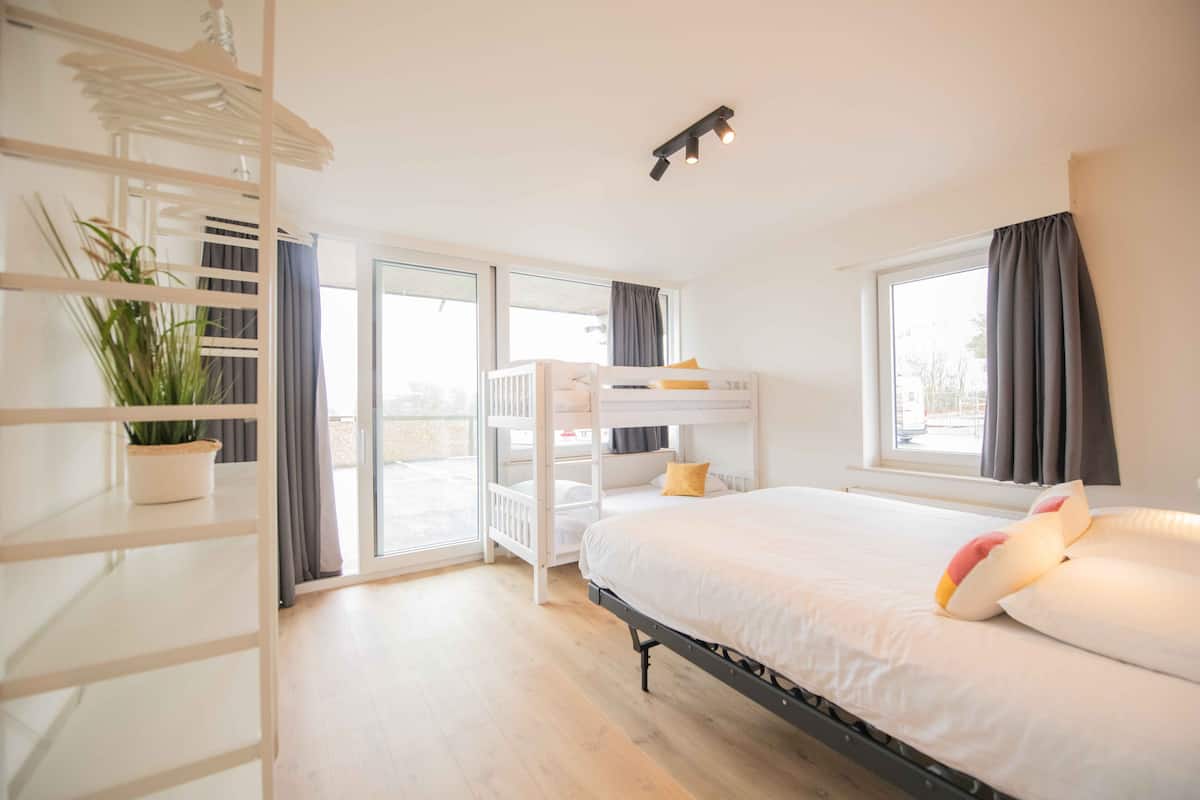 Une chambre avec des lits superposés, une plante en pot et une fenêtre avec des rideaux.