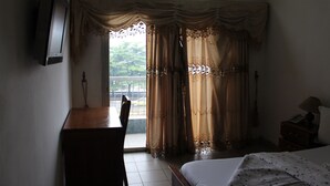 Ein Hotelzimmer mit Bett, Schreibtisch, Stuhl, Fernseher und Vorhängen.