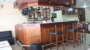 Eine Bar mit Holztresen, mehreren Barhocker und einem Barkeeper.