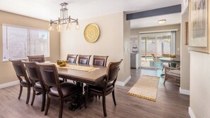 Une salle à manger avec une grande table en bois, six chaises, un lustre et un élément décoratif mural.