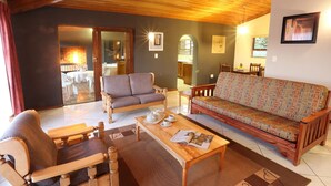 A cozy living room with a wooden sofa, a patterned sofa, and a wooden coffee table with cups and a magazine.