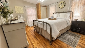 A bedroom with a bed, dresser, nightstand, and a ceiling fan. - The Cottage on College - Pets & Parking (Brandon)