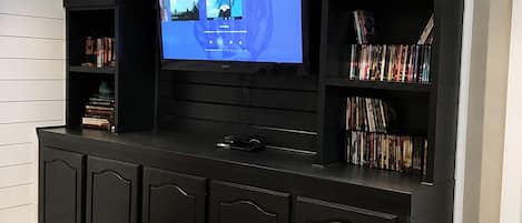 Un meuble de rangement moderne pour appareils multimédias, doté d’un téléviseur à écran plat, d’étagères intégrées et d’une console.