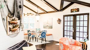 A dining area with a table and chairs, a chandelier, and a view of the outdoors through large windows.