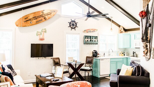 A spacious living room with a dining area, kitchen, and a large window.