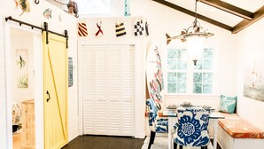A dining area with a table and chairs, a bench, a window with a view, and a door with a yellow handle.