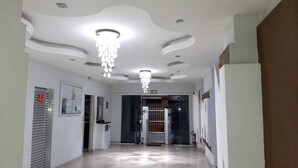 Ein Flur mit modernem Deckenstil, einer Chandelierleuchtre und einer Tür mit der Aufschrift "SAÍDA".