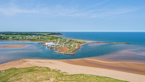 A coastal town with a pier extending into the sea, surrounded by residential buildings and a sandy beach. - Beautiful View of Rustico Bay (North Rustico)