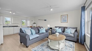 A modern living room with two grey sofas, a wooden coffee table, and a blue patterned rug. - Beautiful View of Rustico Bay (North Rustico)