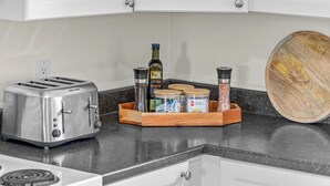 A kitchen counter with a toaster, a wooden cutting board, and a spice rack with jars and bottles. - Beautiful View of Rustico Bay (North Rustico)