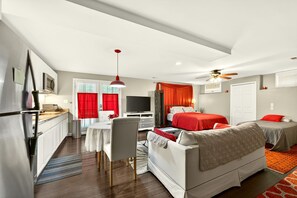 Una habitación de hotel compacta con kitchenette, comedor, sofá y cama.