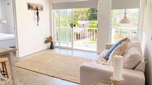 A modern living room with a sofa, a coffee table, and a large window with a view of the outdoors. - SALT by the Sea - Unit 2 (Port Macquarie)