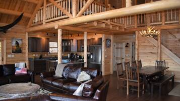 Un intérieur spacieux de chalet en bois, comprenant un salon, un coin repas, une cuisine et un escalier.