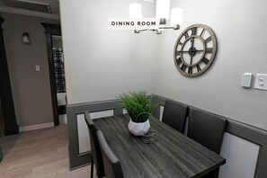 Enjoy meals in this stylish dining room with a dark wood dining table, black chairs, and a large wall clock.