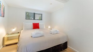 Una camera da letto moderna con un letto, un comodino e una finestra con persiane.