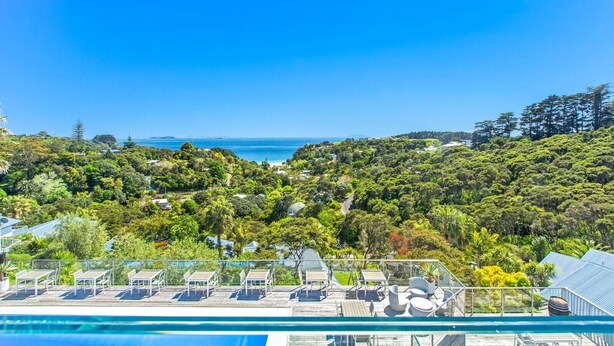 Un resort con piscina, poltrone a sdraio e vista sull'oceano.