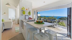 Una cucina moderna con una grande isola, una zona pranzo con posti a sedere all'aperto e vista sull'oceano.