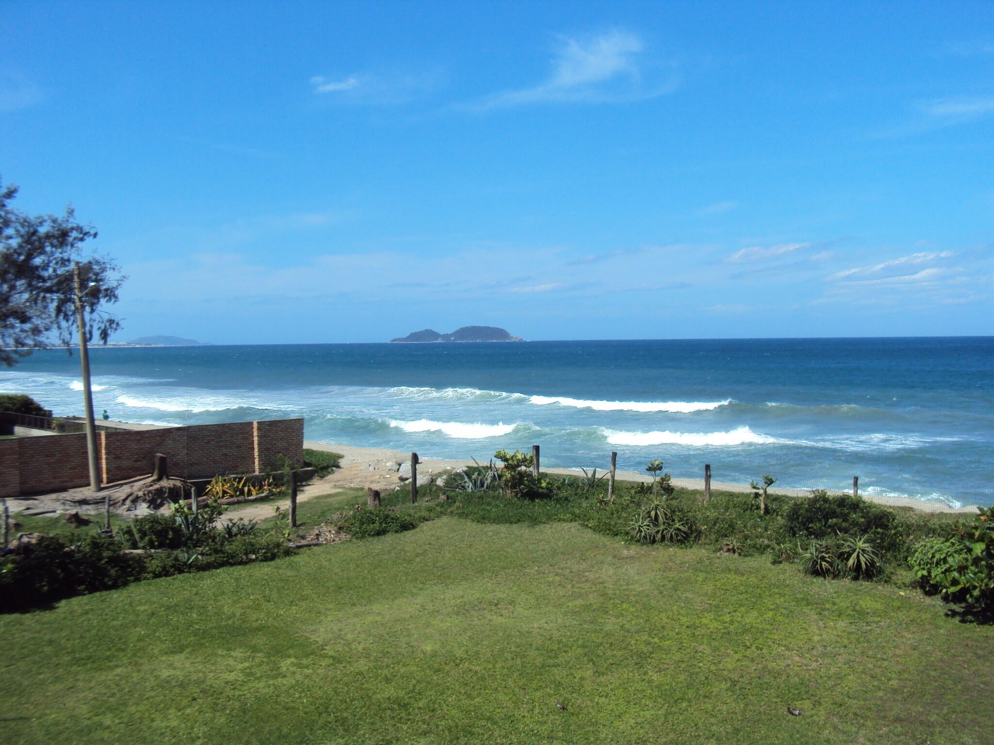 A grassy area with a view of the ocean and a distant island.