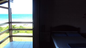 Een kamer met een bed, uitzicht op het strand en een balkon met een leuning.
