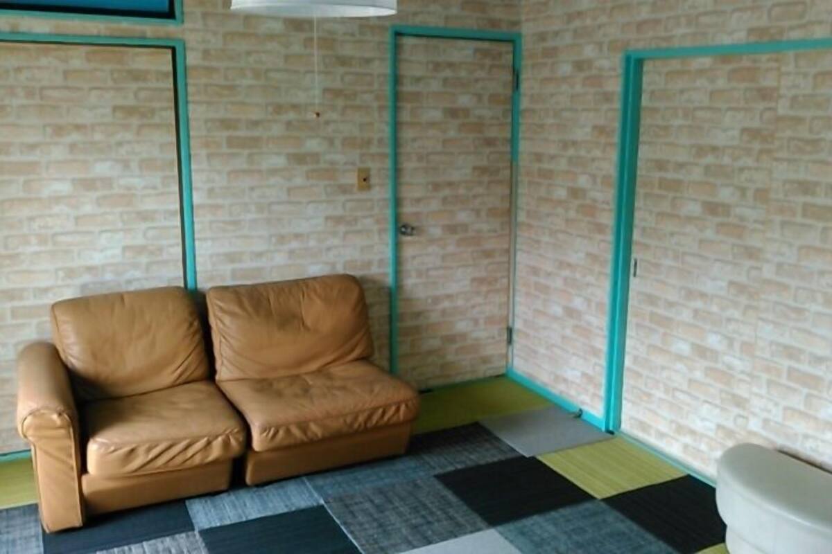 Una habitación con un sofá de cuero marrón, un inodoro blanco y un piso a cuadros.