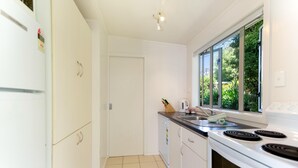 Een moderne keuken met witte kasten, een fornuis en een raam met uitzicht op groen.