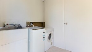 Een kleine wasruimte met een wasmachine en een wasbak.