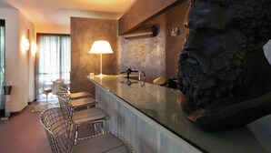 Un'area bar moderna con un elemento centrale dallo stile scultoreo, sgabelli da bar e una lampada.