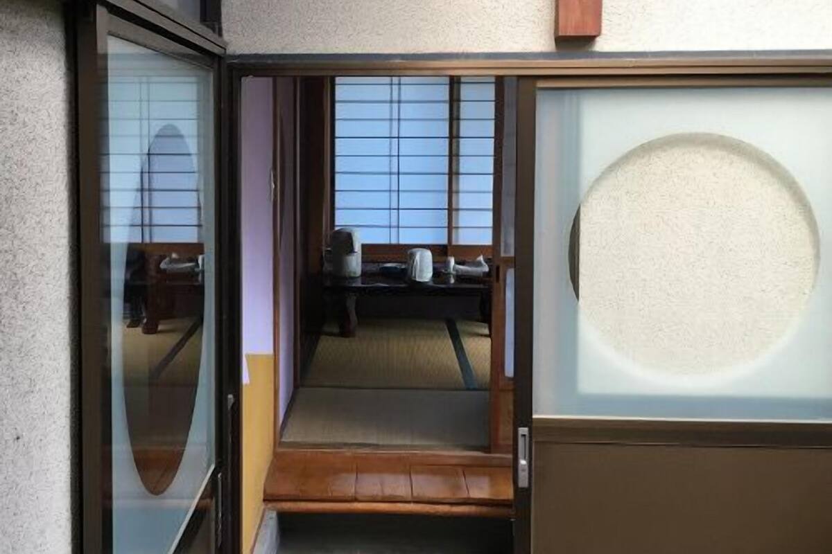 A traditional Japanese room with sliding doors, tatami flooring, and a view of the outside.