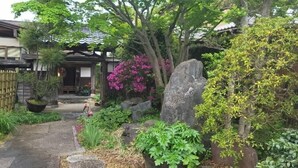 A traditional Japanese garden with a stone pathway, large rocks, and flowering plants. - Masugataya Inn (Tako)