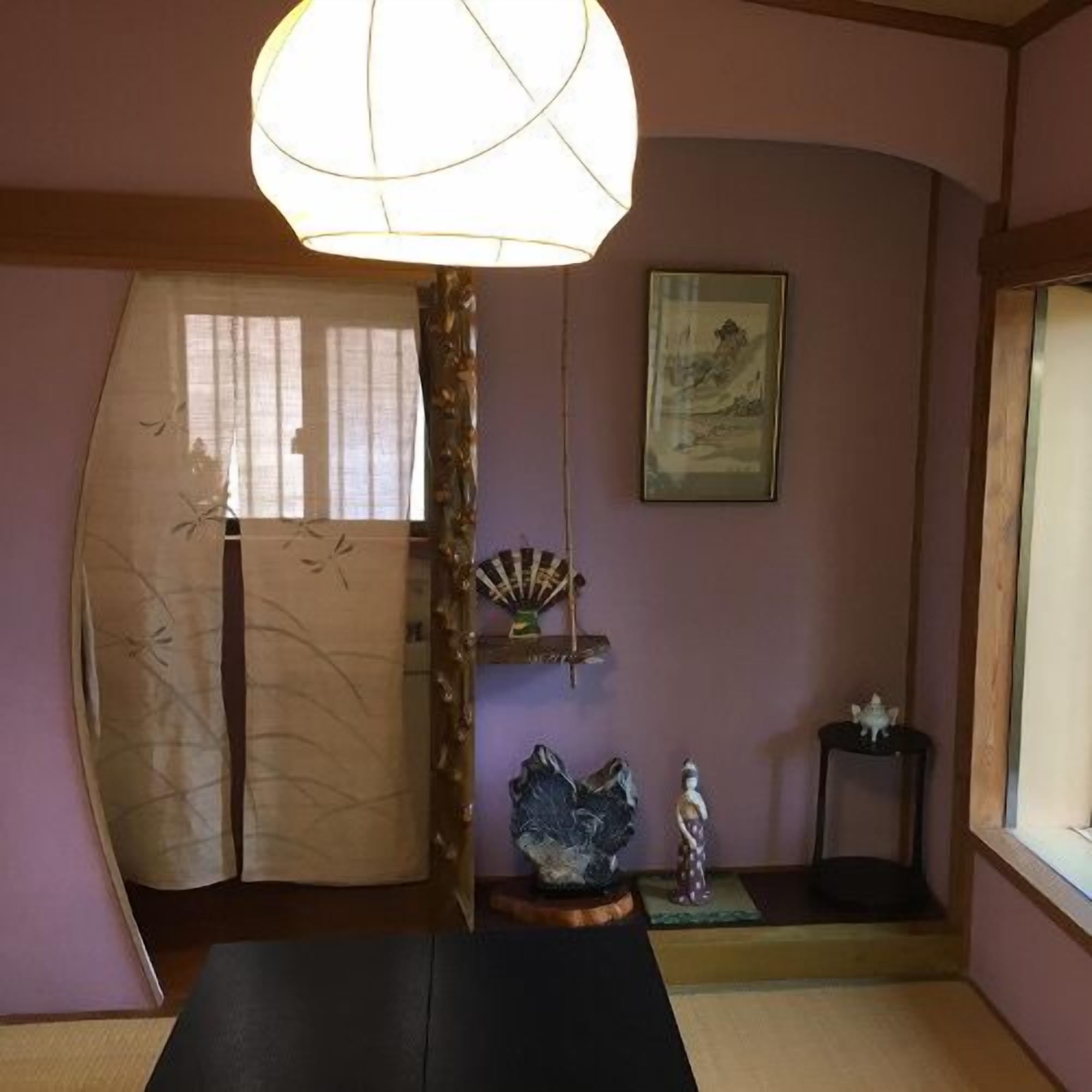 Una habitació japonesa tradicional amb tatami, un panell shoji, una làmpada penjant i un quadre a la paret.