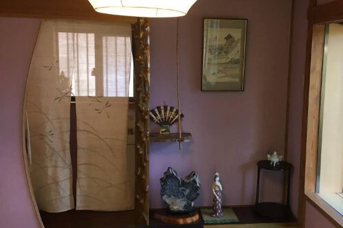 A traditional Japanese room with tatami flooring, a shoji screen, a hanging lamp, and a painting on the wall.