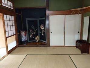 A traditional Japanese room with tatami flooring, shoji screens, a sliding door, and a small cabinet.