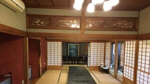 A traditional Japanese room with tatami flooring, sliding doors, and a view of a dining area. - Masugataya Inn (Tako)