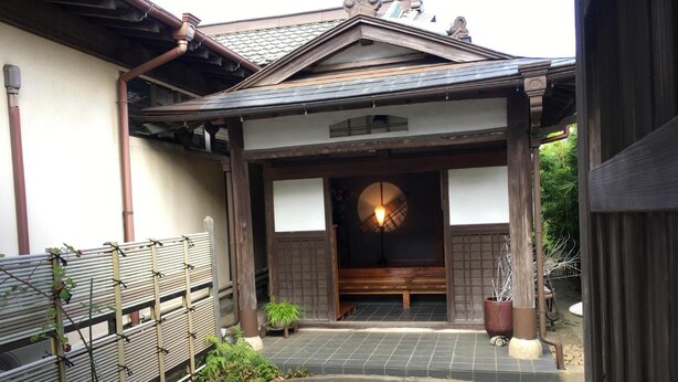 A traditional Japanese building with a tiled entrance, a wooden bench, and a potted plant. - Masugataya Inn (Tako)