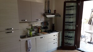 A modern kitchen with white cabinets, a gas stove, and a window with a striped curtain.